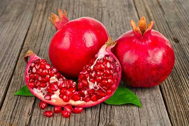 segar dari buah delima yang terbelah menunjukkan biji-biji merahnya yang berkilau, menggambarkan sumber alami antioksidan dan vitamin yang bermanfaat untuk kesehatan jantung dan kulit