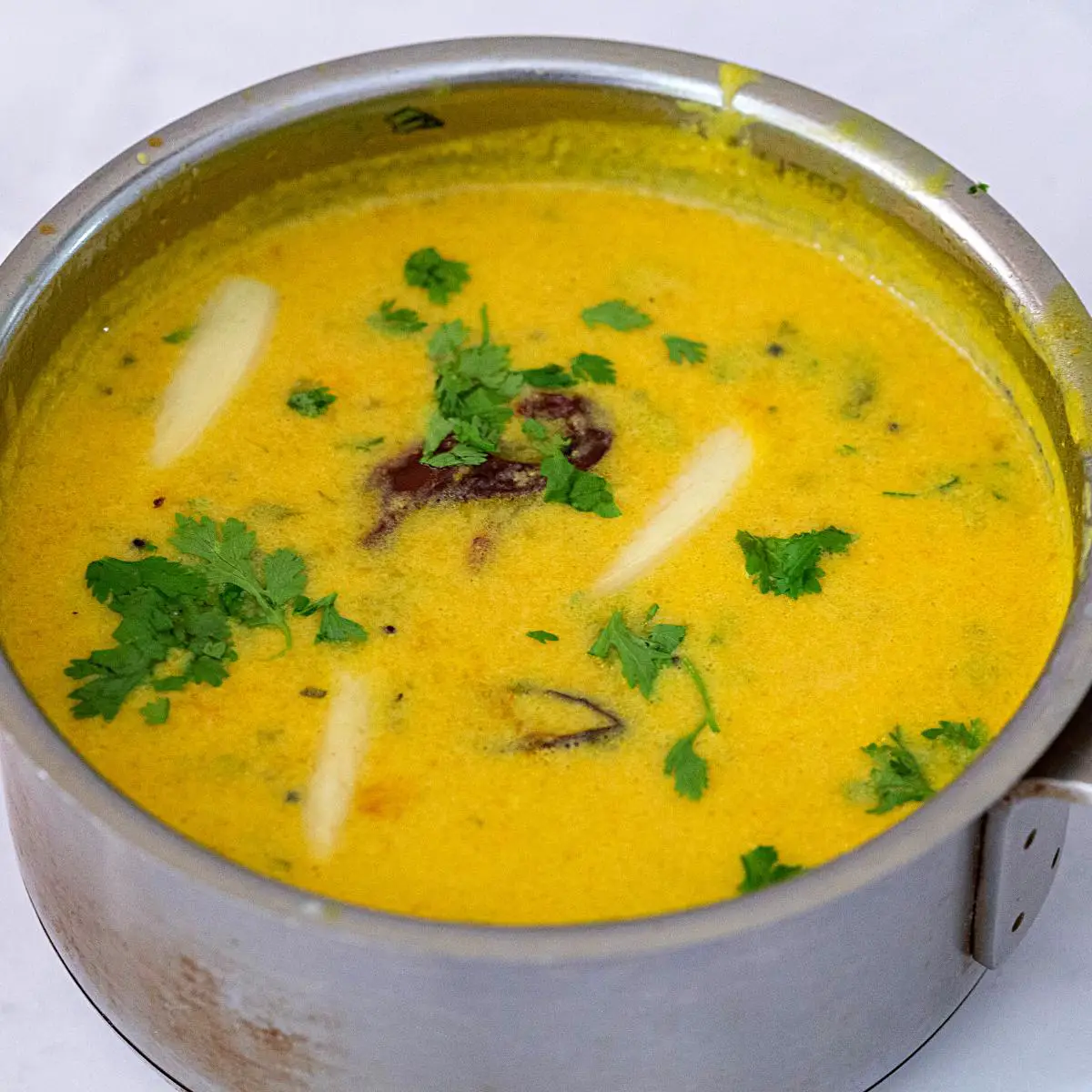  A serving of tangy Gujarati kadhi with a hint of sweetness, accompanied by rice. 